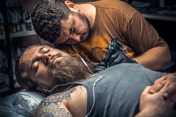Професійний татуювач створює татуювання в студії татуювання
 - Фото, зображення