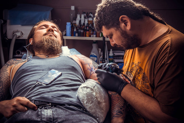 Tatuaje profesional hace tatuaje en estudio
 - Foto, Imagen