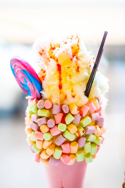 Unusual milkshake decorated with candies, marshmallows, whipped cream - Photo, image