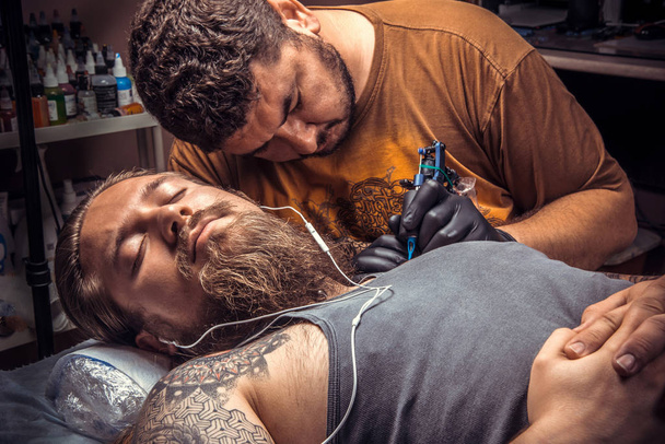 Artista profesional del tatuaje que muestra el proceso de hacer un tatuaje en el estudio del tatuaje
 - Foto, Imagen