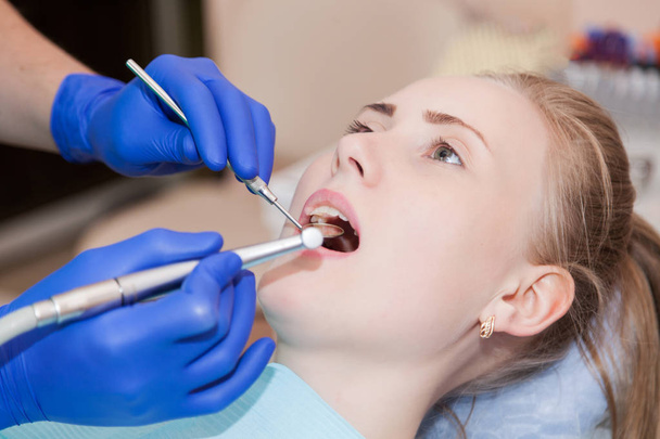 Γυναίκα στην καρέκλα του οδοντιάτρου κατά τη διάρκεια μια οδοντιατρική διαδικασία.  - Φωτογραφία, εικόνα