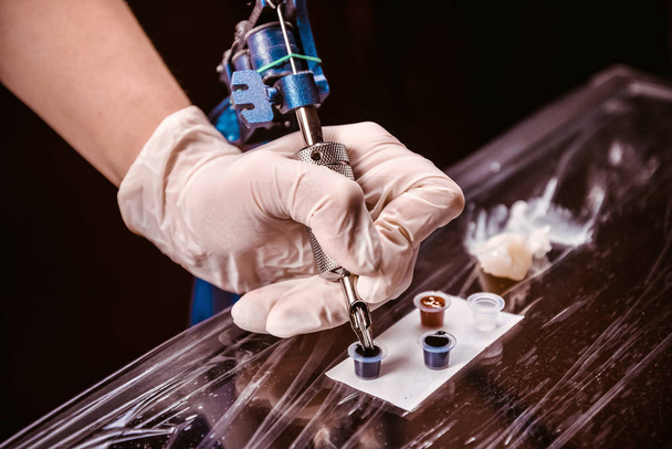 Tätowierer gewinnt den Farbstoff in einer Tätowiermaschine - Foto, Bild