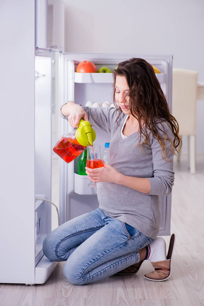 Donna incinta vicino al frigorifero in cerca di cibo e snack - Foto, immagini