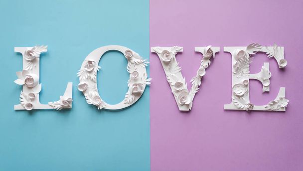 Photo inscription love made of leaves and flowers on blue and purple background - Фото, изображение