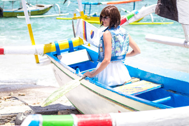 Сексуальная молодая тропическая женщина в солнечных очках позирует в лодке. Тропический остров Бали, Индонезия
. - Фото, изображение