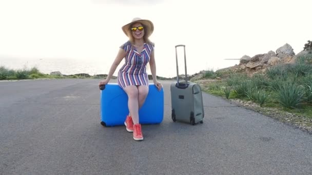 Ευτυχισμένος νεαρή γυναίκα σε διακοπές σε ένα καπέλο με μια βαλίτσα - Πλάνα, βίντεο