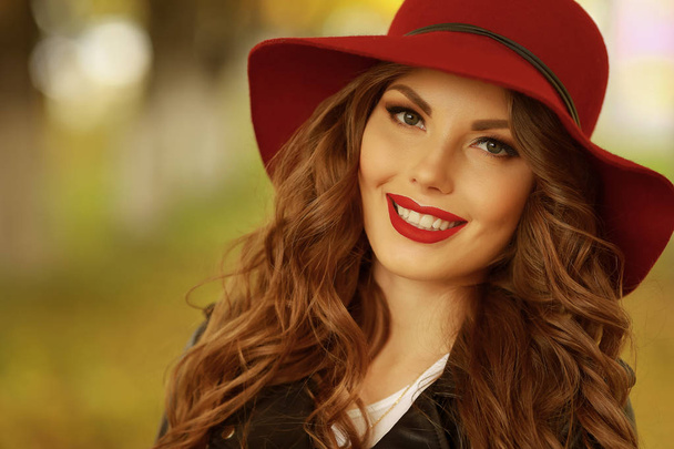 Женщина улыбается с идеальной улыбкой и белыми зубами в парке и смотрит в камеру. - Фото, изображение