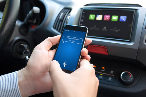 man hand in car holding phone with app personal assistant - Fotó, kép