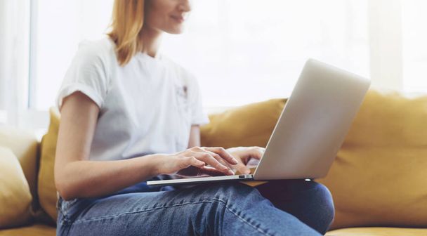 Atractivos mensajes de escritura femenina en una computadora portátil mientras está sentada en casa
 - Foto, Imagen