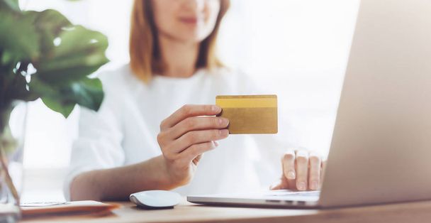 Mujer feliz utilizando el ordenador portátil y tarjeta de crédito para las compras en línea en casa
 - Foto, imagen