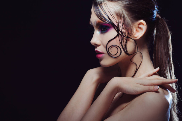 Young beautiful girl bright makeup with a wet look shine, dark background - Photo, image