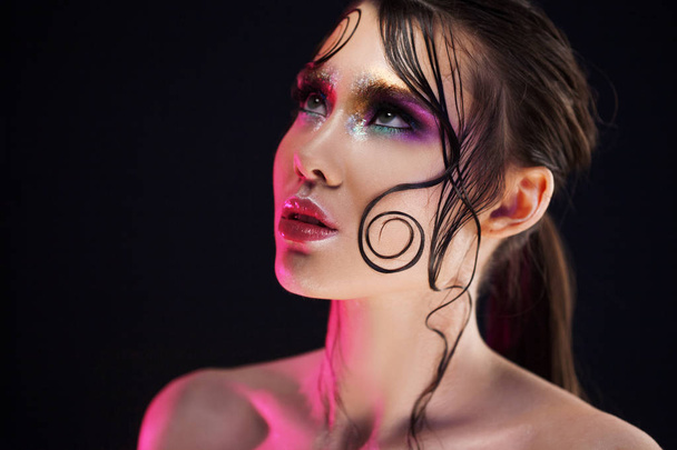 Young beautiful girl bright makeup with a wet look shine, dark background, pink light, disco style - Φωτογραφία, εικόνα