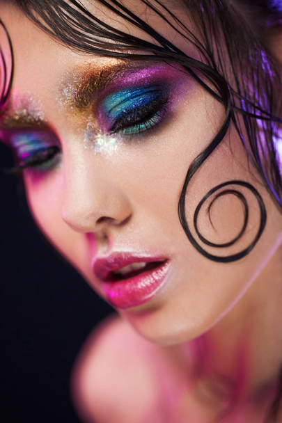 Young beautiful girl bright makeup with a wet look shine, dark background - Foto, afbeelding