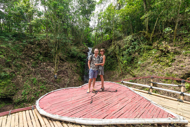 Lövés szerető fiatal Nászutas pár állt össze az esőerdők. Pár szerelmes közelében egy vízesés, a dzsungelben, Bali szigetén, Indonézia. - Fotó, kép