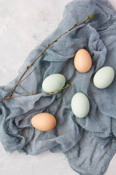 Raw eggs lie on a cotton wool napkin, next to it lies a branch - Фото, изображение