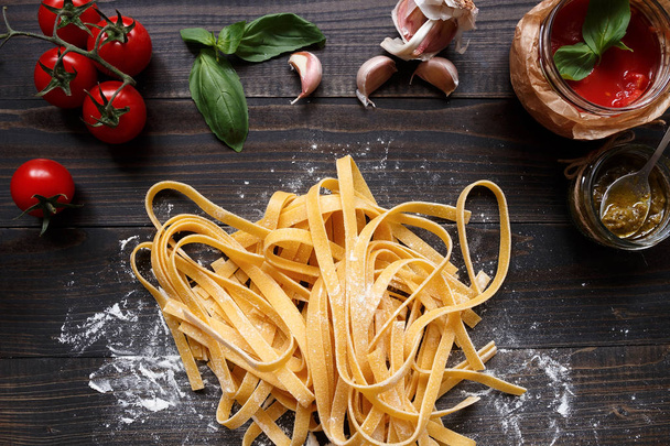 Fresh homemade pasta and vegetables on the dark wooden table top view - 写真・画像