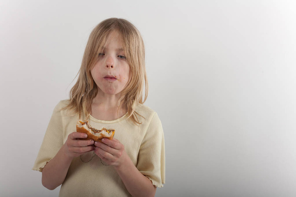 Adorable young girl presenting unhealthy eating with a cheesebur - Zdjęcie, obraz