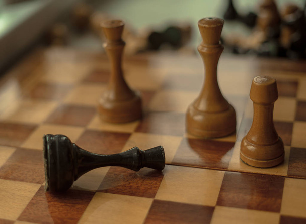 Der schwarze König wird schachmatt gesetzt und fällt auf das Schachbrett - Foto, Bild