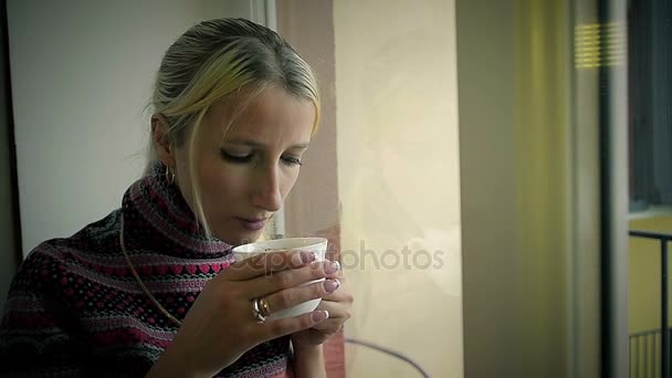 Close-Up menina triste bebendo café em casa e olhando para fora da janela
 - Filmagem, Vídeo