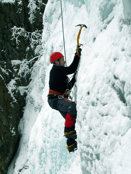 Man climbing frozen waterfall - Foto, afbeelding