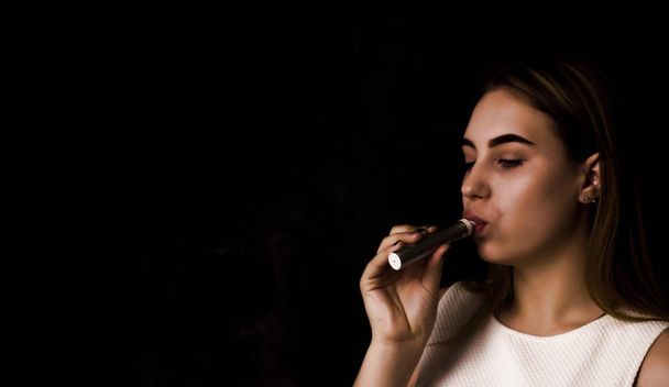 Pretty young girl uses electronic cigarette - Foto, Bild