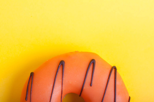 Orange donut with icing on a yellow background. Top view. Minimal concept - Photo, Image