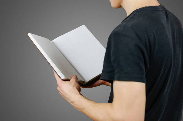 Closeup of guy in black t-shirt holding blank open white book on - Foto, Bild
