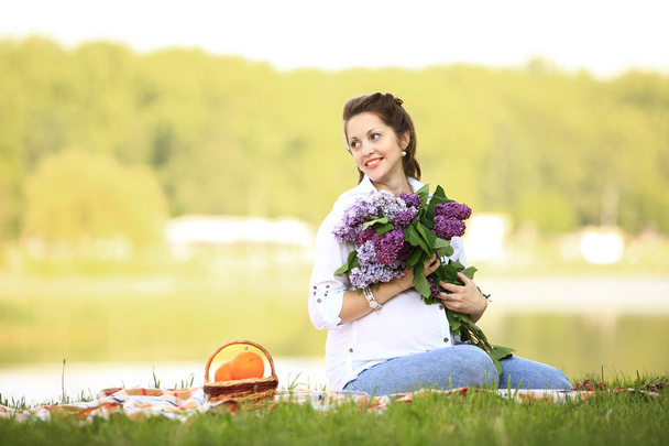 portrait of happy pregnant woman with bouquet of lilacs on a pic - Fotó, kép