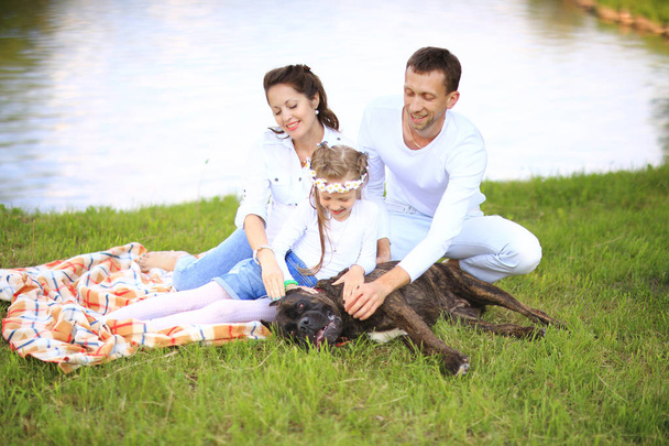 happy family with pet dog at picnic in a Sunny summer day. pregn - Фото, изображение