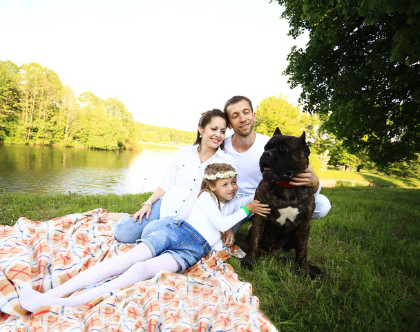 szczęśliwa rodzina z psem na pikniku w słoneczny letni dzień. pregn. - Zdjęcie, obraz
