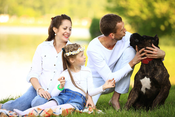 happy family with pet dog at picnic in a Sunny summer day. pregn - Foto, afbeelding