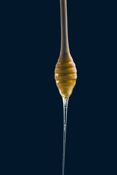 Honey stick on black background - Foto, afbeelding