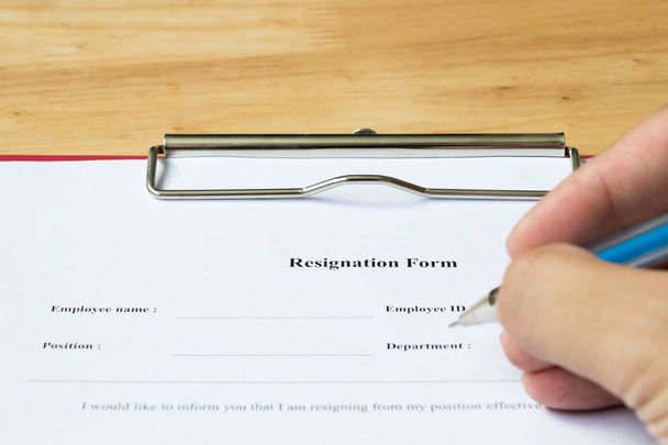 Resignation form with hand hold the pen for filling on wood desk background - Photo, Image