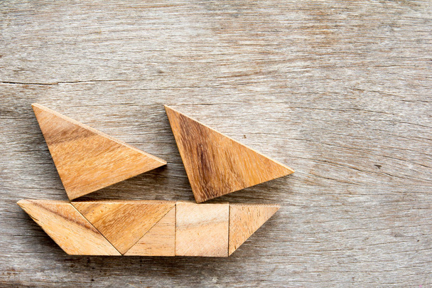 Puzzle tangram en voilier sur fond bois (Concept pour start-up, entrepreneur ou trouver une cible
) - Photo, image