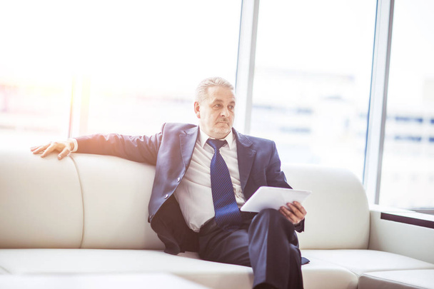 successful businessman with digital tablet sitting on sofa in the office. - Фото, зображення