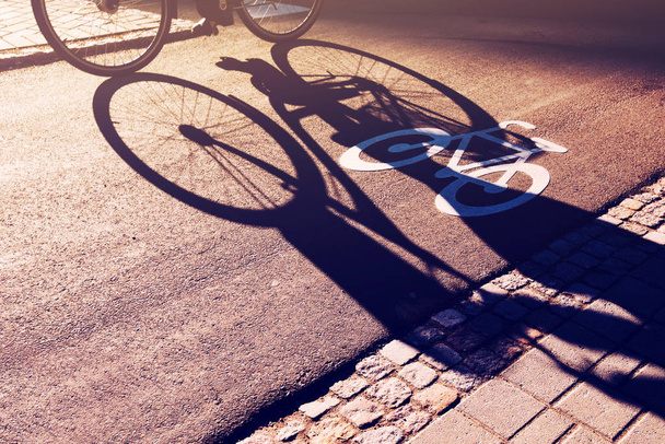 Shadow of unrecognizable cyclist on bicycle lane - 写真・画像