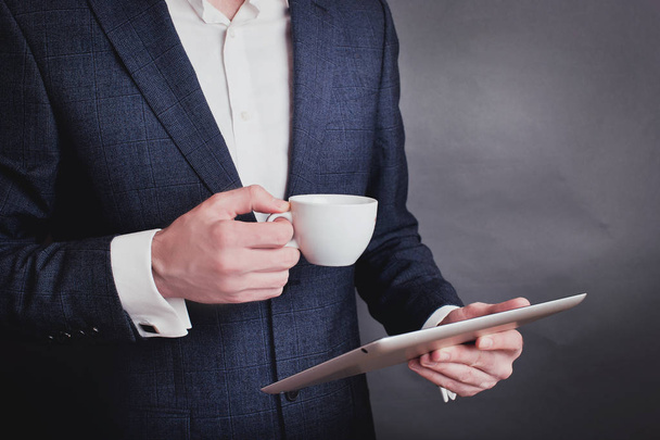 Businessmen in suit holding the cup of coffee and tablet. - Foto, Imagen