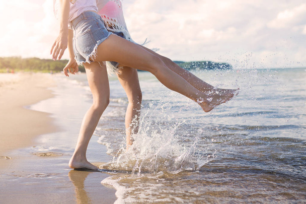 Two girls standing barefoot in the sea splashing - Zdjęcie, obraz
