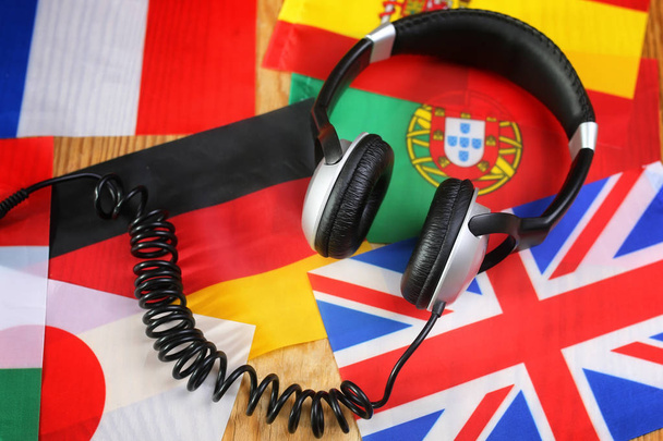 auriculares y bandera del idioma del curso en una mesa
 - Foto, Imagen