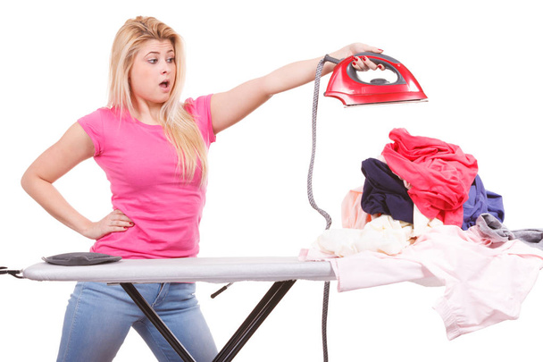 Shocked woman holding iron about to do ironing - Fotoğraf, Görsel