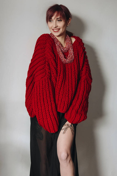 Young woman in red oversized sweater and black skirt - 写真・画像