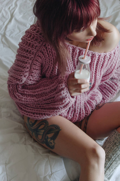 Beautiful young woman in pink oversize sweater in bed - Фото, зображення