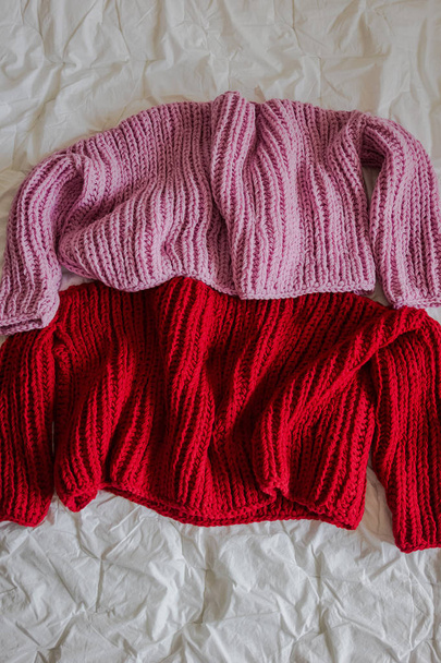 Pink and red sweaters on a bed - Foto, Imagen