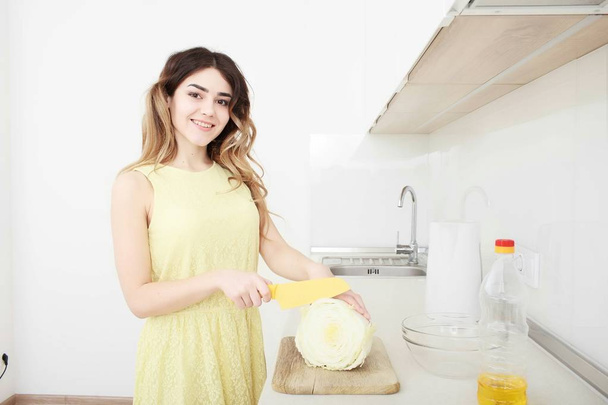 Girl cook cuts cabbage in the kitchen - Φωτογραφία, εικόνα