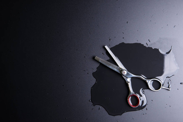 Стильные профессиональные парикмахерские ножницы, стрижка волос на черной спине
 - Фото, изображение