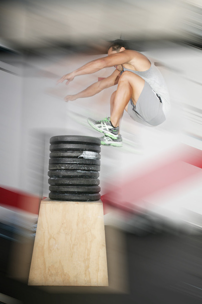 Urheilullinen mies hyppää yli paljon painoja
 - Valokuva, kuva