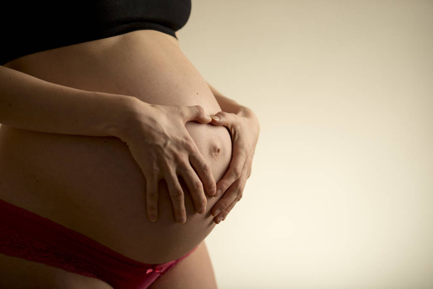 Mulher grávida segurando sua barriga nua
 - Foto, Imagem