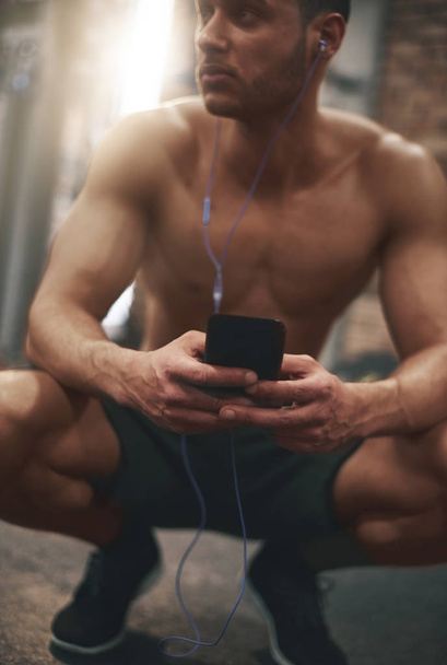 man listening music while sitting at gym - Foto, Bild