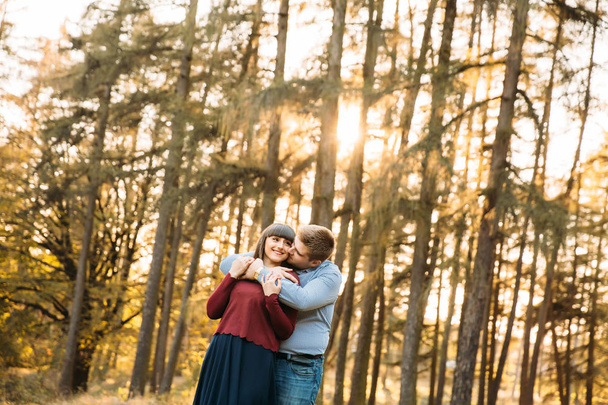 Los amantes se besan al atardecer en un bosque de pinos
 - Foto, Imagen
