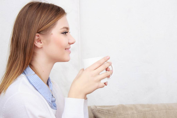 жінка сидить на дивані у своїй вітальні і п'є каву
 - Фото, зображення